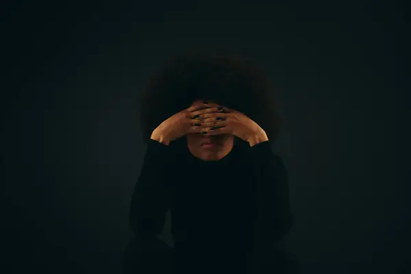 A stylish African American woman in trendy attire covers her face with her hands. — Stock Photo