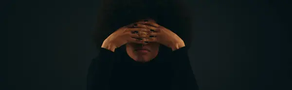 A stylish African American woman in trendy attire covers her face with her hands. — Stock Photo