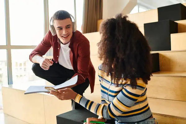 Un hombre y una mujer multiculturales se sientan en las escaleras, profundamente pensados, compartiendo un momento de reflexión y contemplación - foto de stock