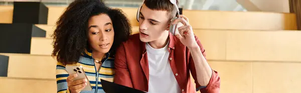 A diverse pair, one African American girl, engaged with a cell phone screen indoors, sharing a moment of connectivity and information — Stock Photo