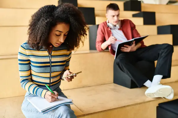 A woman of African American descent, sitting on stairs, focused on writing on a piece of paper — Stock Photo