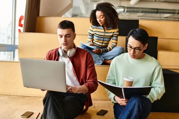 Los estudiantes multiculturales se sientan en el piso con computadoras portátiles, inmersos en el entorno de aprendizaje digital en la universidad o la escuela secundaria - foto de stock