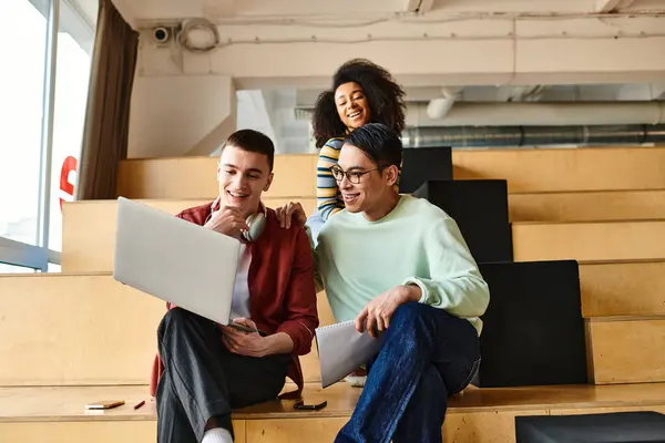 Grupo multicultural de estudiantes, incluida una niña afroamericana, sentados juntos en la parte superior de una escalera interior - foto de stock