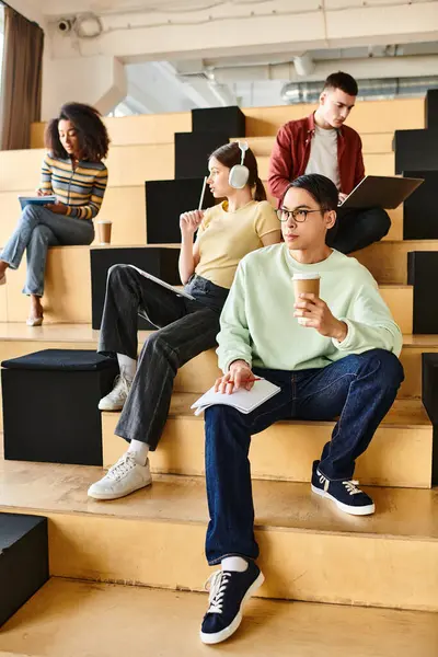 Group of multicultural students, including an African American girl, sitting together on a staircase indoors — Stock Photo