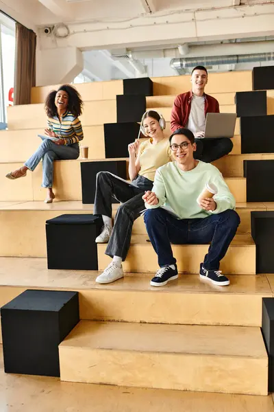 Um grupo multicultural de estudantes sentados juntos em uma grande escadaria, envolvidos em conversa e estudo — Fotografia de Stock