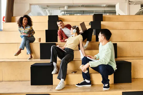 Estudiantes multiculturales de diferentes orígenes se sientan en una escalera, absortos en la conversación - foto de stock