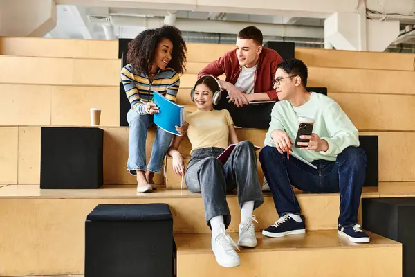 Estudiantes multiculturales, incluida una chica afroamericana, se sientan juntos en los escalones, entablando una animada conversación - foto de stock
