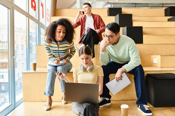 Los estudiantes multiculturales colaboran alrededor de una computadora portátil, participando en una animada discusión y compartiendo ideas - foto de stock