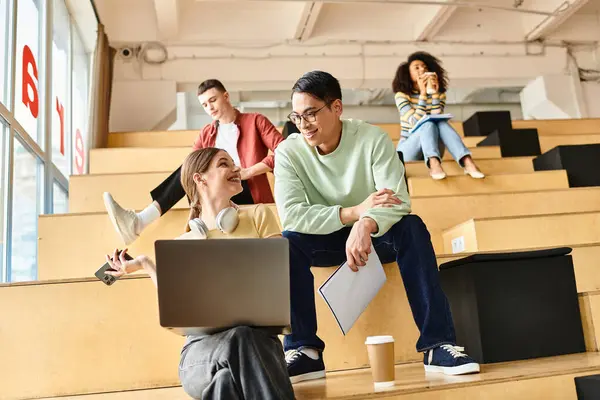 Estudantes multiculturais sentam-se em bancadas, focadas em laptops, em um ambiente educacional em uma universidade ou ensino médio. — Fotografia de Stock