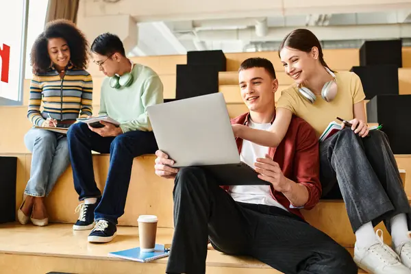 Gli studenti multiculturali siedono su gradini, assorbiti nei computer portatili a fini educativi. — Foto stock