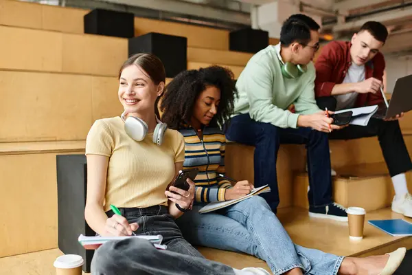 A diverse group of students enjoy each others company while sitting on a set of steps. — Stock Photo
