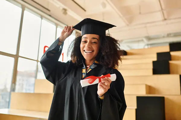 An African American woman proudly wears a graduation cap and gown, celebrating her academic achievements. — Stock Photo