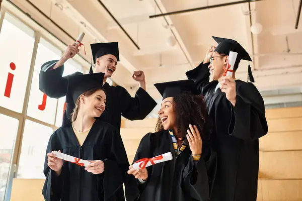 A diverse group of individuals in graduation gowns and caps proudly holding their diplomas in celebration. — Stock Photo
