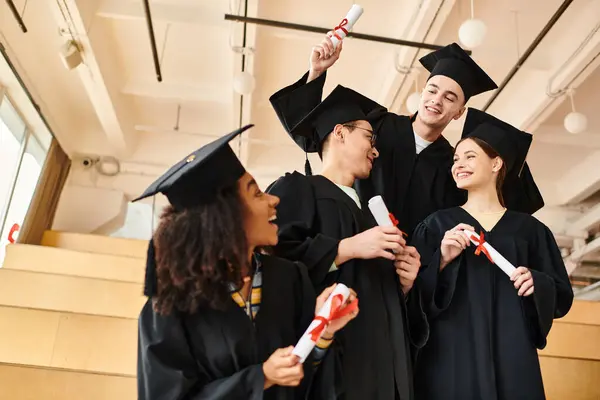 Un grupo de graduados vestidos de colores y gorras de pie juntos, llenos de alegría y celebración en su día de graduación. - foto de stock