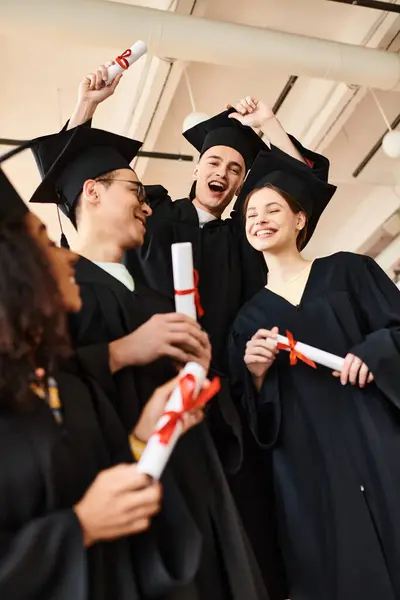 Un groupe d'étudiants diversifiés en robes et casquettes de fin d'études se réunissent pour célébrer leurs réalisations scolaires. — Photo de stock