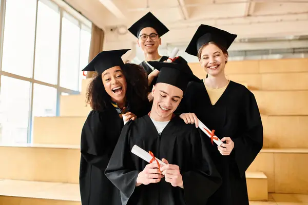 Un groupe d'étudiants en robes et casquettes de fin d'études posant joyeusement pour une photo pour célébrer leur réussite scolaire. — Photo de stock