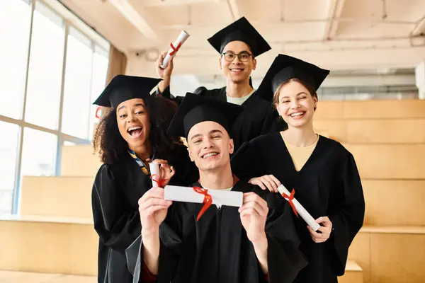 Um grupo de estudantes de diferentes origens, vestindo vestidos de formatura e bonés, posando alegremente para uma celebração comemorativa. — Fotografia de Stock
