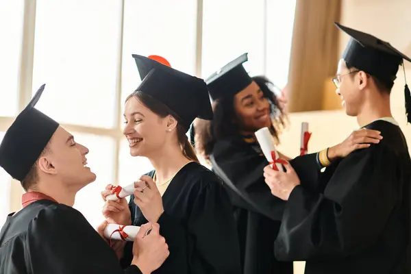 Un grupo multicultural de estudiantes en trajes de graduación y gorras celebrando sus logros académicos con sonrisas. - foto de stock