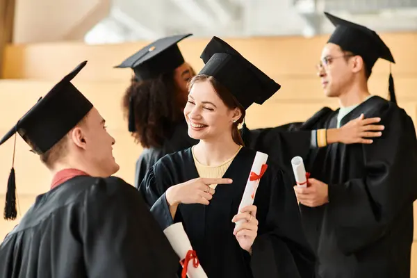 Різноманітна група студентів у випускних сукнях і шапках, що стоять разом, святкуючи їх академічний успіх. — стокове фото