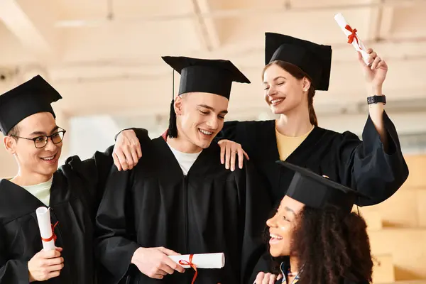 Un variado grupo de estudiantes en trajes de graduación y gorras posando felices para una foto después de completar su viaje académico. - foto de stock