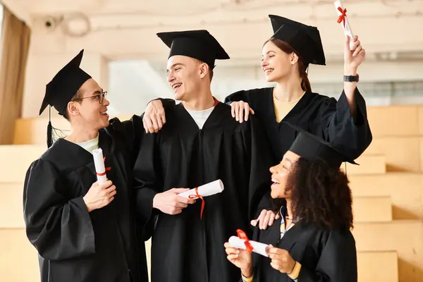 Un grupo diverso de estudiantes, incluyendo individuos caucásicos, asiáticos y afroamericanos, posan alegremente en batas de graduación.. - foto de stock
