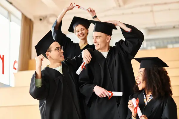 Un grupo de jóvenes estudiantes de diversos orígenes étnicos celebrando en sus vestidos y gorras de graduación. - foto de stock