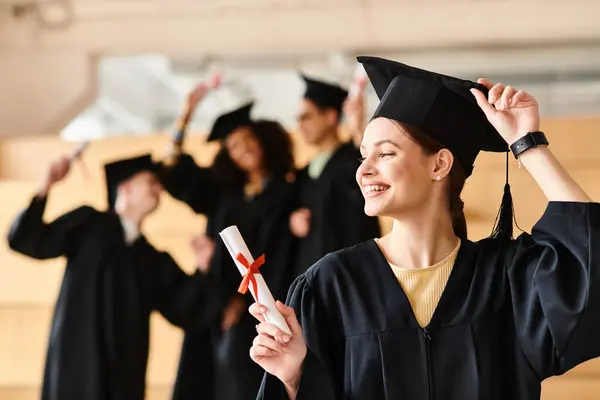 Woman of diverse heritage proudly holds her graduation diploma in a gown and cap. — Stock Photo