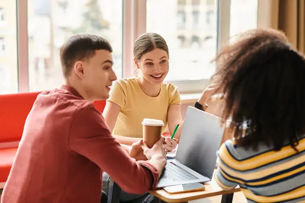 Un groupe diversifié d'étudiants sont assis autour d'un ordinateur portable, engagés dans l'apprentissage collaboratif et la discussion. — Photo de stock