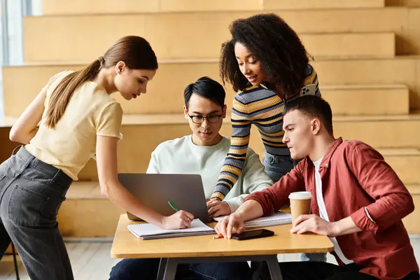 Diverse group of students focused on laptop work at table in university setting. — Stock Photo