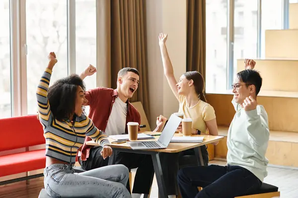 Un groupe diversifié d'étudiants assis autour d'une table avec un ordinateur portable, engagés dans des projets technologiques collaboratifs. — Photo de stock