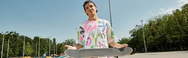 Стильний молодий чоловік тримає свій скейтборд на парковці, готовий вдарити по вулицях своїм наступним трюком. — стокове фото