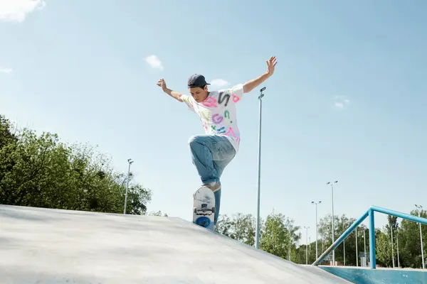A young skater boy riding a skateboard up a ramp in a lively outdoor skate park on a sunny summer day. — Stock Photo