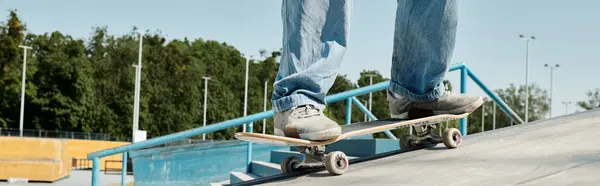 Jeune patineur garçon manèges courageux planche à roulettes sur rail latéral dans le skate park urbain par une journée ensoleillée. — Photo de stock