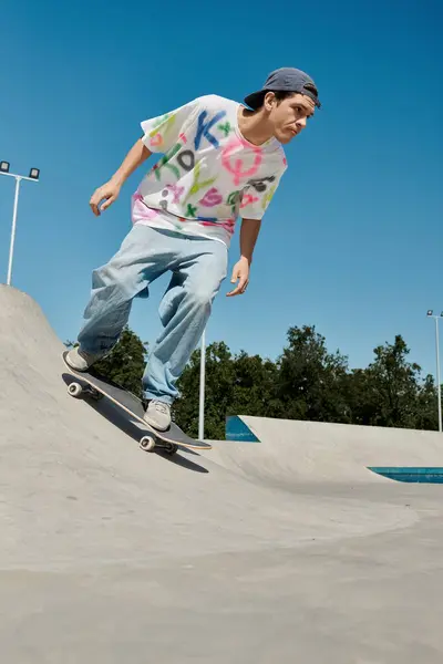A young skater boy fearlessly rides his skateboard down the side of a ramp in a skate park on a sunny summer day. — Stock Photo