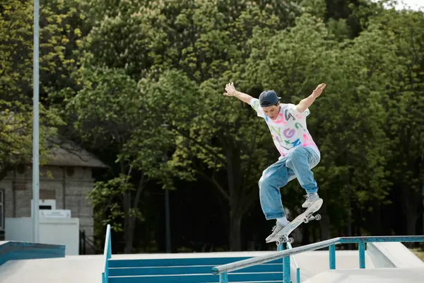 Un jeune patineur habile monte courageusement sa planche à roulettes sur le côté d'un rail dans un skate park en plein air par une journée d'été ensoleillée. — Photo de stock