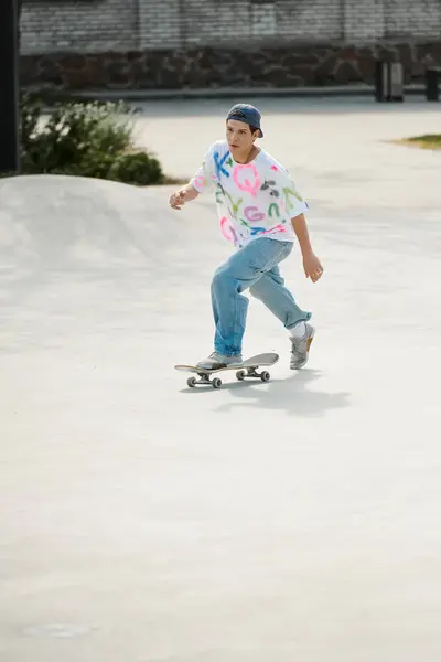 Un joven skater monta con confianza en su monopatín por una rampa de cemento en un parque de skate en un día soleado de verano.. - foto de stock