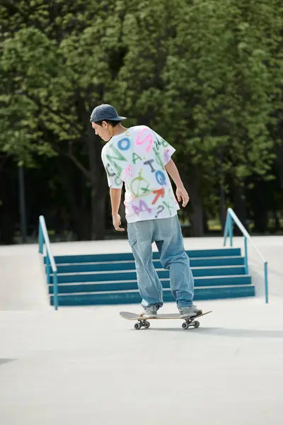 Un joven skater monta con confianza su monopatín por el lado curvo de una rampa en el parque de skate en un día soleado de verano.. - foto de stock