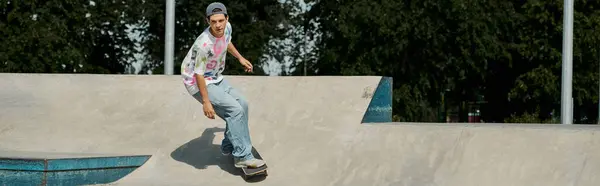 Un giovane skater boy guida impavido uno skateboard sul lato ripido di una rampa in un vivace skate park all'aperto. — Foto stock