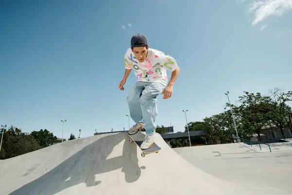 Un joven patinador que realiza un impresionante truco de skate al lado de una rampa en un soleado parque de skate al aire libre. - foto de stock