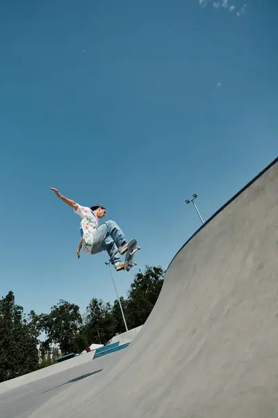 Молодий ковзаняр безстрашно їде на скейтборді вгору по стороні пандуса в галасливому відкритому скейт-парку в сонячний літній день. — стокове фото