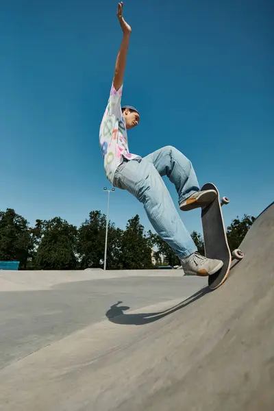 Ein junger Skater-Junge fährt furchtlos mit seinem Skateboard die steile Seite einer Rampe in einem sonnigen Outdoor-Skatepark hinauf. — Stockfoto