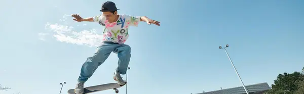 Un joven skater monta sin miedo un monopatín al lado de una rampa en un vibrante parque de skate al aire libre en un soleado día de verano.. - foto de stock