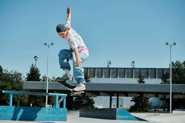Молодий ковзаняр обманює гравітацію, коли він їде на скейтборді в бік пандуса в яскравому відкритому скейт-парку в сонячний літній день. — стокове фото