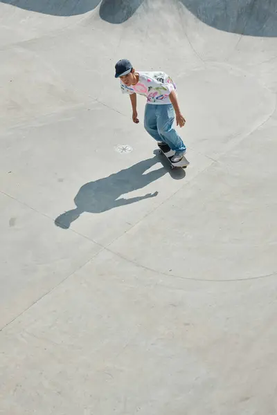 Un joven monta su monopatín por una rampa en un parque de skate en un día soleado de verano. - foto de stock