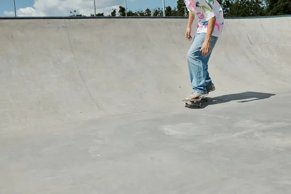 Молодий ковзаняр обманює гравітацію, коли він їде на скейтборді в бік пандуса в сонячному парку. — стокове фото
