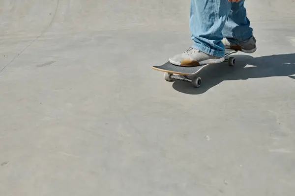 Молодой скейтбордист без особых усилий катается на скейтборде по гладкой цементной поверхности в ярком открытом скейтпарке в летний день. — стоковое фото