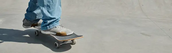 Um jovem patinador mostra suas habilidades enquanto monta um skate em uma superfície de cimento em um vibrante parque de skate urbano em um dia ensolarado. — Fotografia de Stock