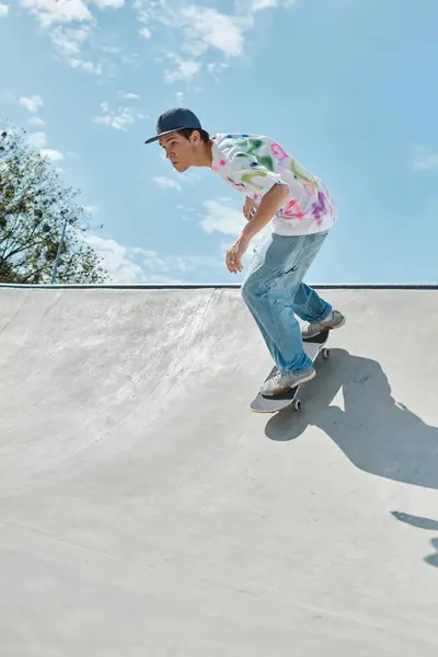 Um jovem skatista ousado monta seu skate até o lado de uma rampa em um parque de skate ao ar livre ensolarado em um dia de verão. — Fotografia de Stock