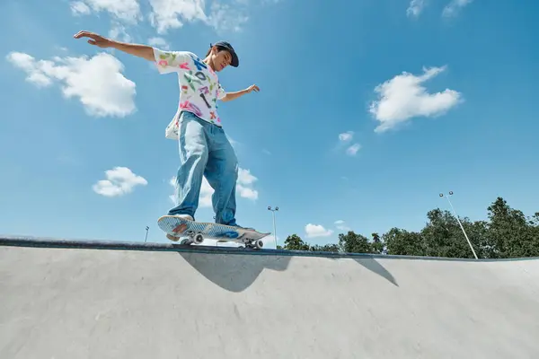 Un joven skater monta su monopatín sin miedo por la empinada rampa en el parque de skate al aire libre en un soleado día de verano.. - foto de stock