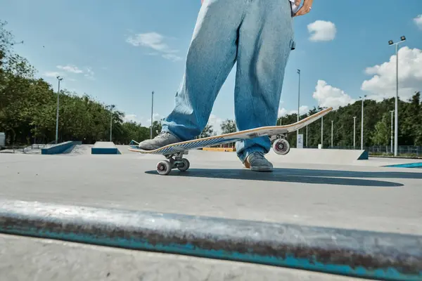 Un jeune patineur monte sur une planche à roulettes au-dessus d'une rampe de ciment dans un skate park lors d'une journée d'été ensoleillée. — Photo de stock